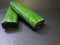 photo of 2 pieces of tempeh wrapped in green banana leaf with black background