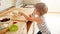 Photo of 3 years old toddler boy rolling dough on wooden board and baking cookies for breakfast. Child cooking on