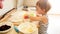 Photo of 3 years old toddler boy rolling dough on wooden board and baking cookies for breakfast. Child cooking on