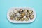 A photo from above of small uncooked quail eggsin white porcelain plate on the blue table. An overhead photo of quail eggs, Easter