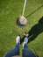 Photo from above of womans legs on grass with golf ball and golf cue before  hole