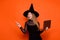 Photo of adorable dreamy girl dressed dark witch dress headwear typing modern device pointing empty space isolated