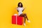 Photo of adorable impressed dark skin lady dressed white clothes sitting huge gift box  yellow color background