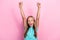 Photo of adorable lucky little child dressed teal t-shirt rising fists screaming isolated pink color background