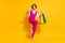 Photo of adorable lucky young woman dressed pink suit holding shopping bags modern gadget isolated yellow color