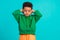 Photo of adorable nice schoolboy with wavy hair dressed green pullover arms cover ears eyes closed  on teal