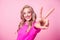 Photo of adorable optimistic girl wavy hairstyle wear stylish pullover arm showing v-sign good mood isolated on pink