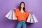 Photo of adorable pretty lady wear orange clothes hold many packs enjoy nice shopping isolated on purple color