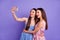 Photo of adorable shiny two best friends dressed summer clothes tacking portrait modern gadgets isolated purple color