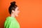 Photo of adorable shiny young woman wear green hoodie standing profile isolated vivid orange color background