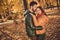 Photo of affectionate passionate couple guy hug kiss girlfriend in autumn september forest town park wear coats scarf