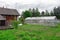 Photo of aged wooden house with glass greenhouse