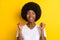 Photo of amazed cheerful dark skin young woman raise fists winner isolated on yellow color background