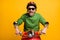 Photo of amazed funny guy ride moped wear helmet spectacles green pullover isolated yellow color background