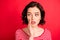 Photo of amazed girl attempting to tell her girl secret as quietly as possible while isolated with red background