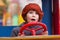 Photo of amazed girl in cap keeping red steering wheel on a playground. Close up portrait of little girl opening mouth and
