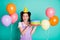 Photo of amazed lady hold cake open mouth many balloons wear violet overall paper cone cap isolated teal color