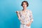 Photo of amazed lovely lady point thumb empty space hold hand pocket wear white print shirt isolated on blue color