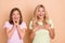 Photo of amazed mother and daughter hold hands chest cheeks news sale isolated on beige color background