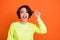 Photo of amazed shocked cheerful woman hold hand hair salon conditioner isolated on orange color background