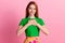 Photo of appreciative gorgeous kind woman with ginger hair dressed green t-shirt hold palms on chest isolated on pink