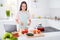 Photo of asian ethnicity housewife mixing fresh vegetables salad ingredients cooking tasty vegan meal using online