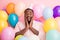 Photo of attractive dark skin guy amazed unexpected birthday surprise arms cheekbones surrounded many air balloons wear