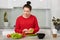 Photo of attractive future mother, holds lettuce, prepares vegetable salad for breakfast, dressed in casual red clothes, cooks at
