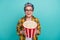 Photo of attractive retired woman bucket popcorn excited dressed stylish checkered yellow clothes isolated on aquamarine