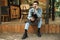 Photo of attractive waiter man sitting on wooden floor while working in cafe or coffeehouse outdoor