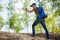 Photo from back of man with backpack and walking sticks on hill