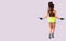 Photo of a back view slim athletic girl with long dark hair wearing short top and yellow shorts using jumping rope for