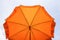 Photo of a beach umbrella on the blue sky,Beach umbrella.One vibrant orange colored sunshade against vivid blue sky and white