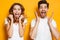 Photo of beautiful admired couple man and woman in basic clothing screaming in surprise or delight and touching cheeks, isolated