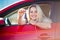 Photo of beautiful blonde woman with keys sitting in red car with open window