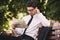 Photo of beautiful businessman in suit sitting on bench in green