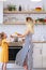 Photo of beautiful woman in long striped dress and daughter in kitchen