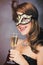 photo of beautiful young woman in mask with wineglass of champagne on the wonderful black studio background
