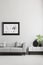 Photo in a black, thick frame on a gray wall, white sideboard and a gray sofa in a stylish living room interior with place for a P