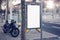 Photo blank lightbox on bus stop in the modern city. Authentic motobike parking close. Horizontal mockup, sunlight