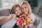 Photo of blonde girl and woman make selfie camera hold flowers tulips indoors inside house apartment