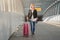 Photo of blonde with pink baggage walking on crosswalk at airport.