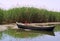 A photo of a boat on a lake near a path full of grass.