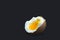 A photo of boiled smash broken hen beige egg on dark blue. Egg`s liquid yolk photo, bright contrast.