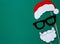 Photo booth colorful props for christmas party - santa hat, glasses, beard on green background.
