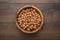 Photo of a bowl full of hazelnuts on the brown wooden table