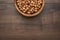 Photo of a bowl full of hazelnuts on the brown wooden table with copy space