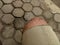 Photo of a boy\'s leg wearing torn brown trousers against a hexagonal brick floor in the background