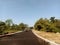 photo of a bright blue sky above a newly paved road with a right and left view of bushes and lush trees