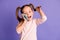 Photo of brown tails haired little girl wear jumper talk on phone amazed hold pigtail isolated on violet color